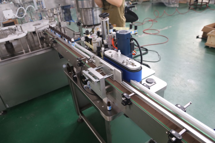 Begi tanta automatikoak botilak eranskailuen etiketatze-makina inguratzen ditu Begi tanta automatikoak botilak eranskailuen etiketatze-makina inguratzen ditu